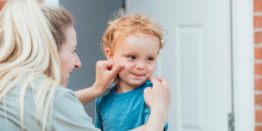 Une maman avec son enfant qui a de la crème solaire sur le visage
