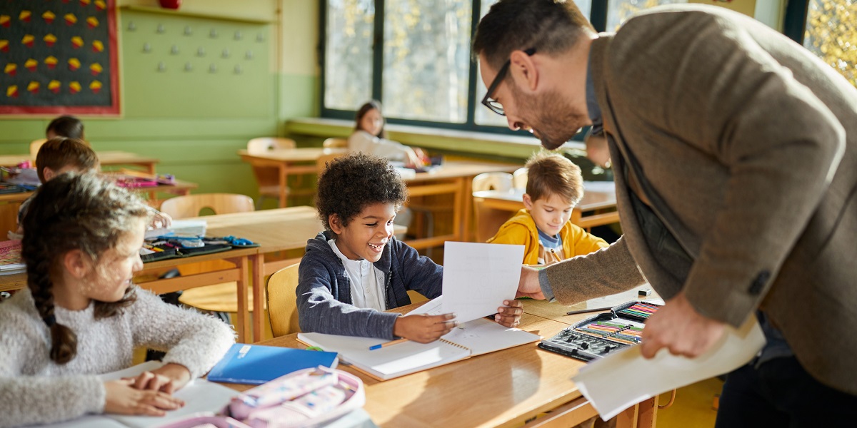 Élèves en classe avec leur enseignant, soulignant la baisse des coûts en crèches et écoles, soutenue par la Ligue des familles