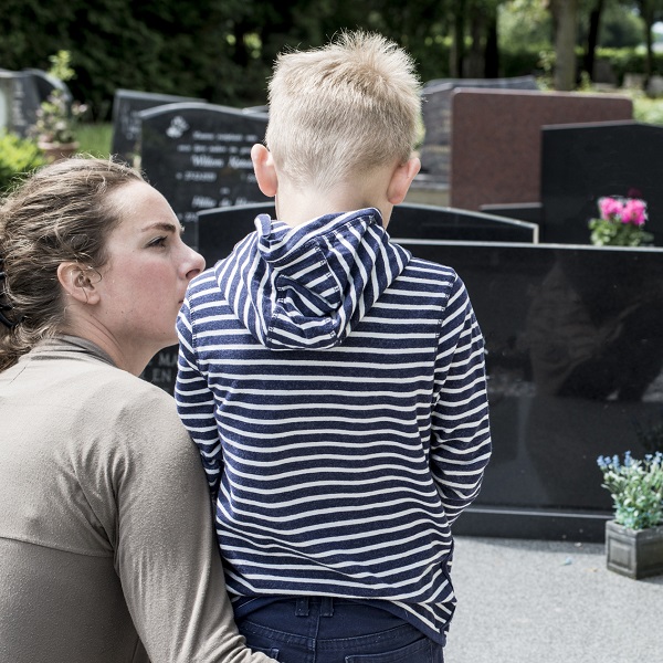 Mère et enfant face à une tombe, un moment qui reflète l'allongement du congé de deuil