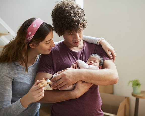 Parents tenant leur nouveau-né, heureux des avancées législatives sur le congé parental 