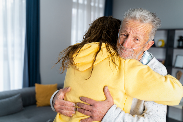 Une femme prend son père malade dans ses bras