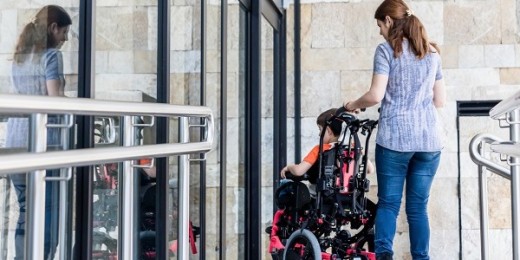Une maman accompagne son enfant en chaise roulante